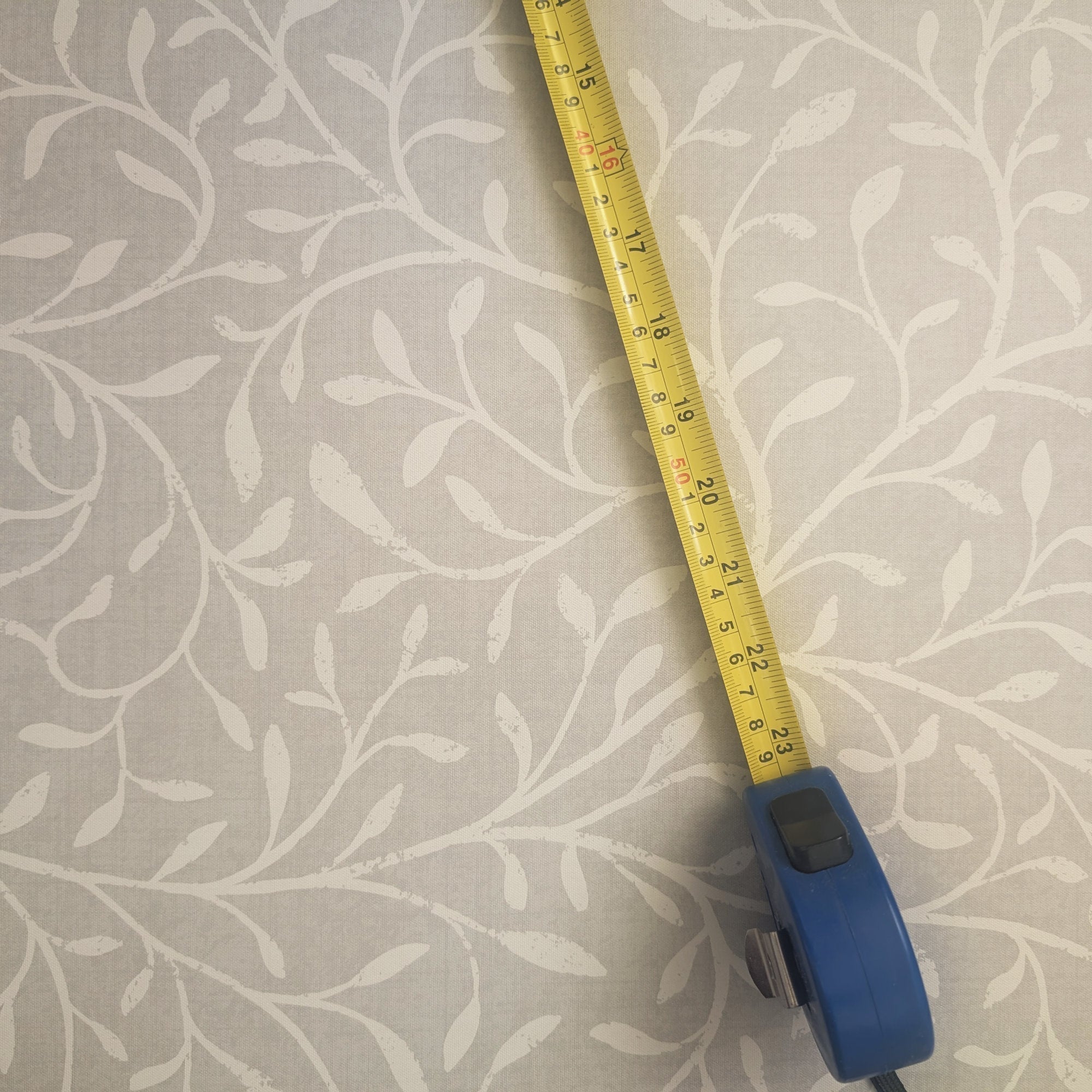 A measuring tape on a wallpaper pattern, illustrating the concept of wallpaper pattern scale.