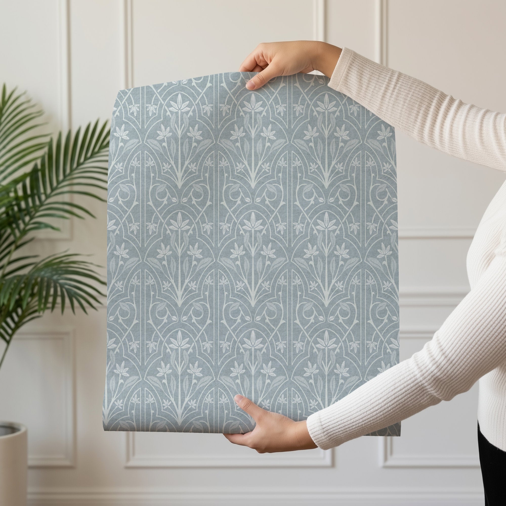 Blue and White Art Nouveau Trellis Wallpaper held by a person, showcasing the modern floral design in a light blue color palette.