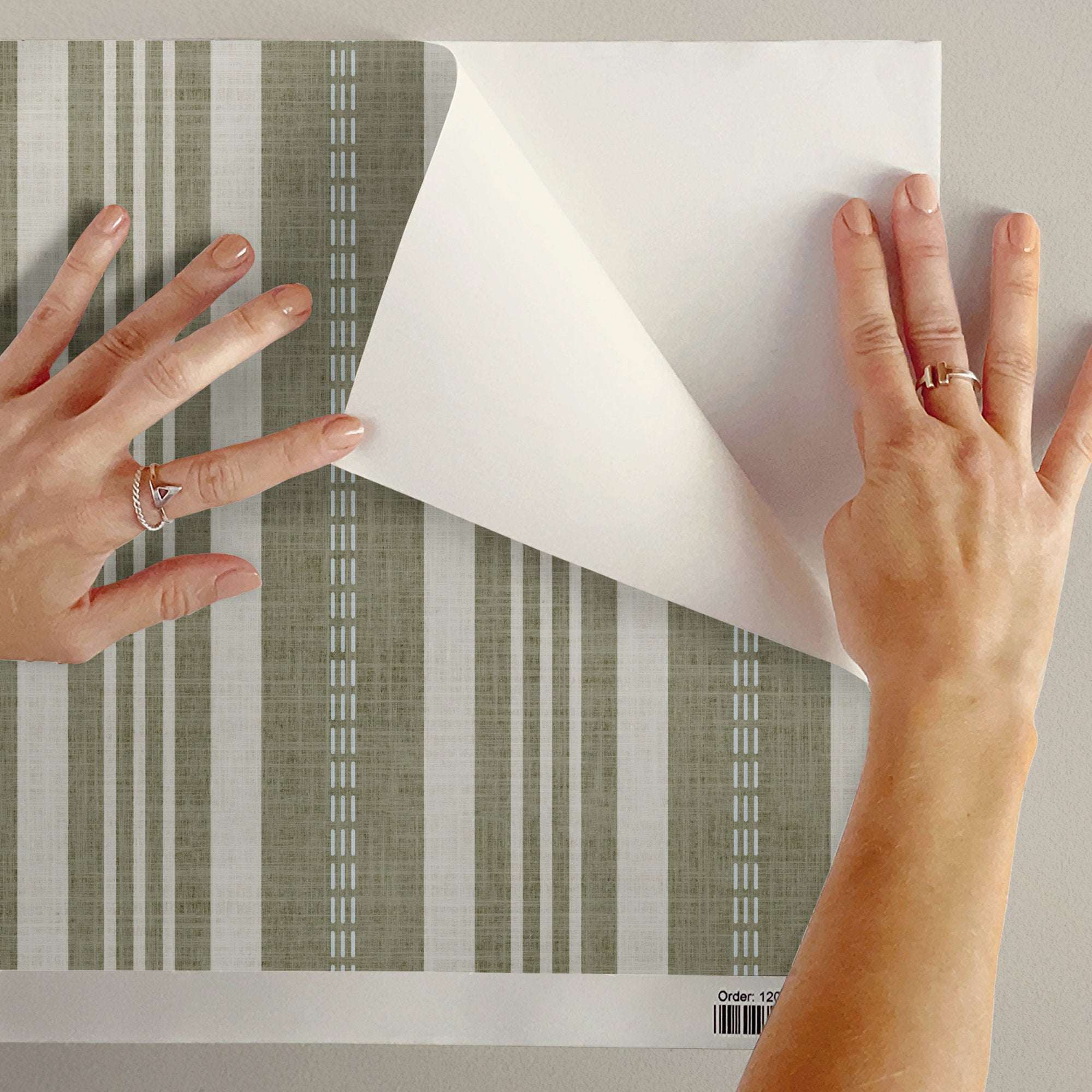 Wallpaper sheet being applied, featuring vertical ticking stripes in sage green and cream