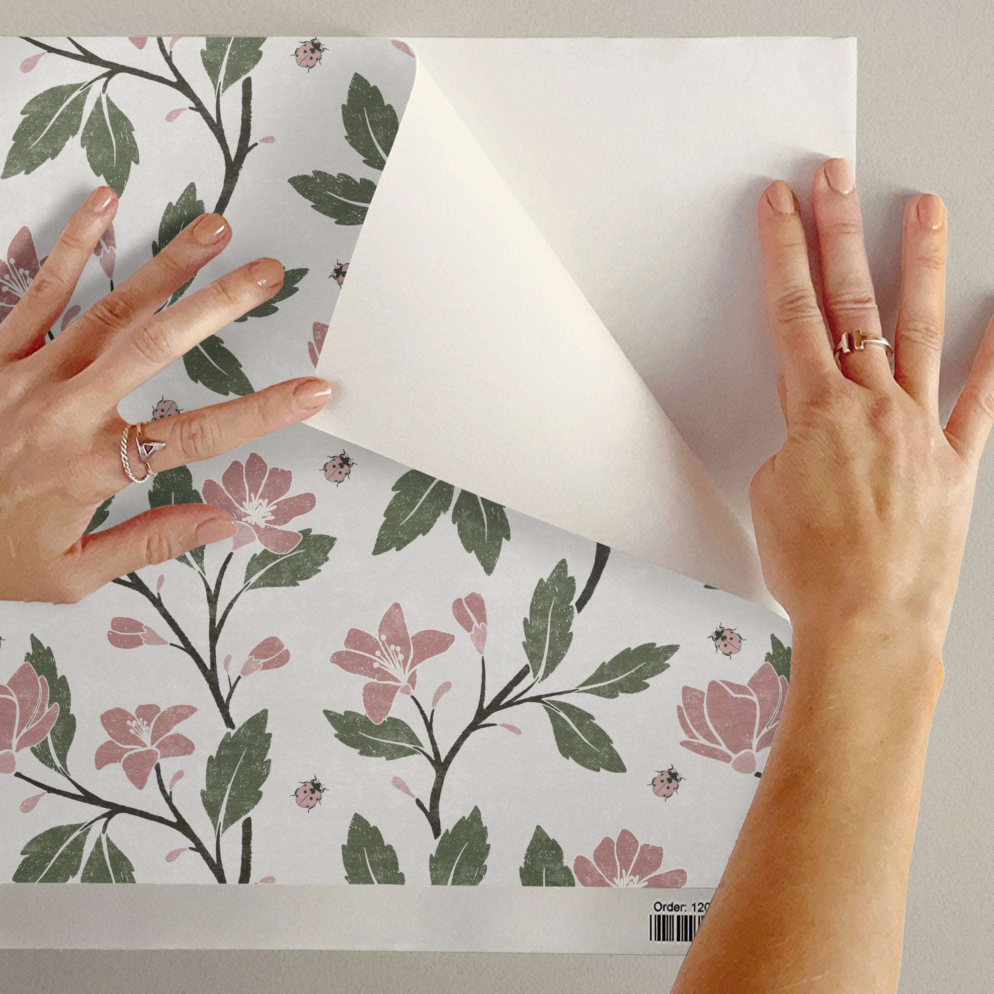 Floral vine wallpaper close-up with pink flowers, green leaves, and ladybirds on light backing
