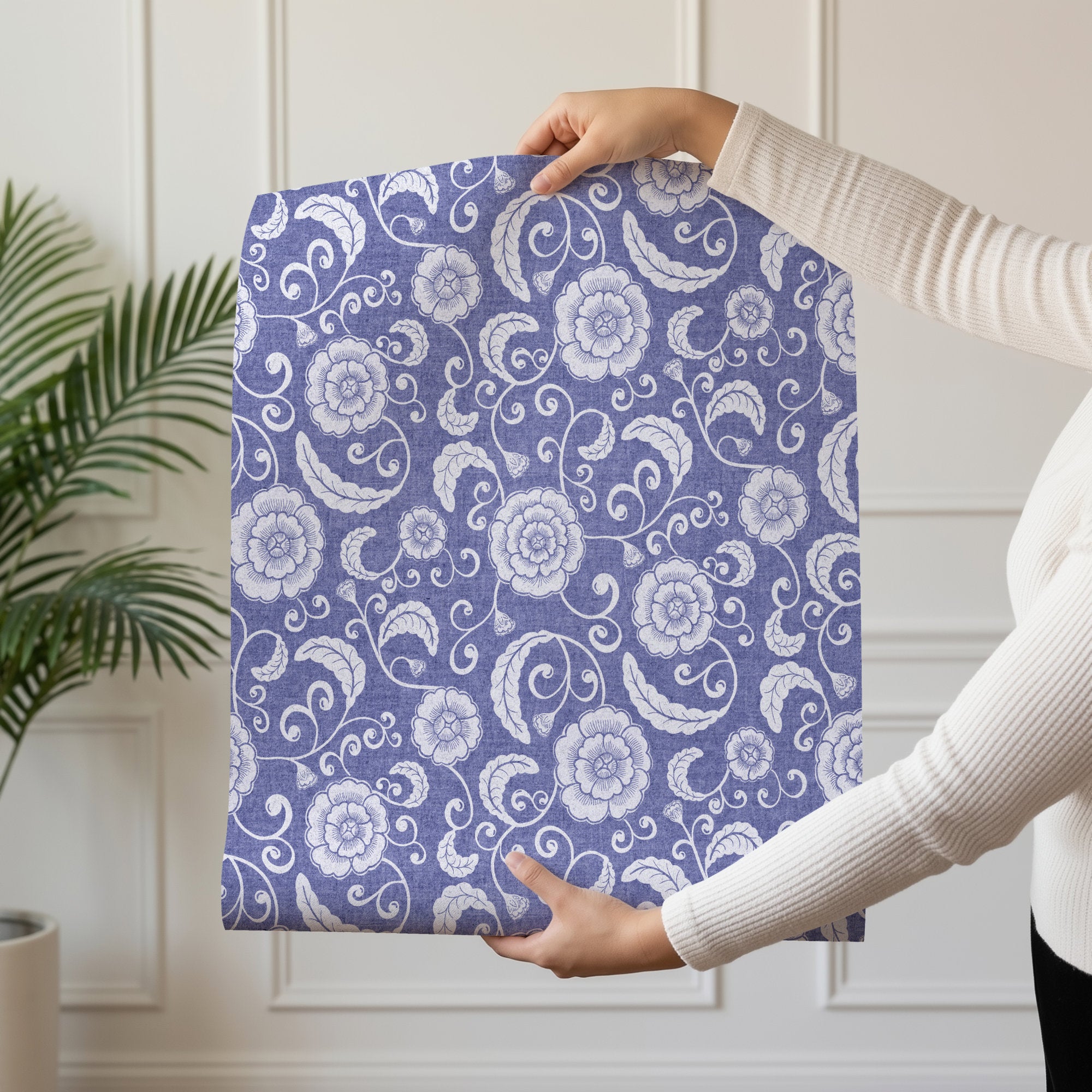 Person holding a roll of blue ginger jar wallpaper with pale porcelain florals