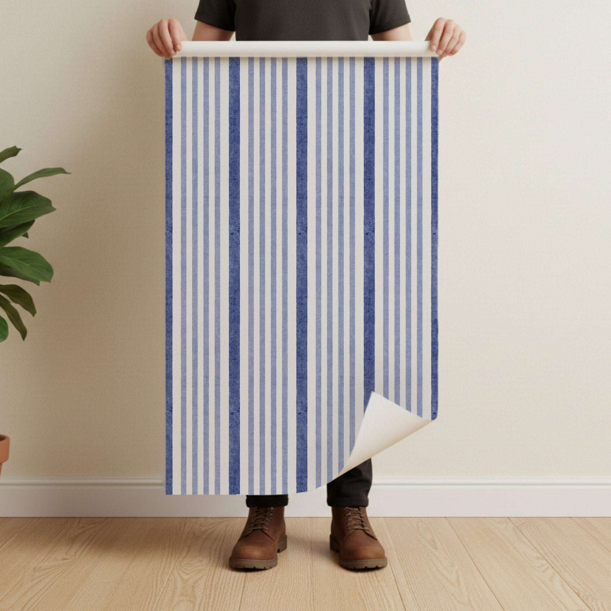 Wallpaper sheet with vertical watercolor-style stripes in dark blue and off-white being held up