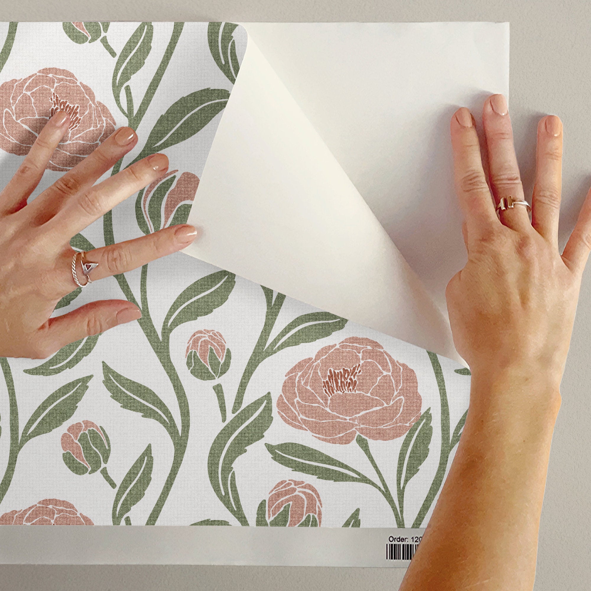 Peeling back blush pink peony flower wallpaper to show the removable peel and stick finish