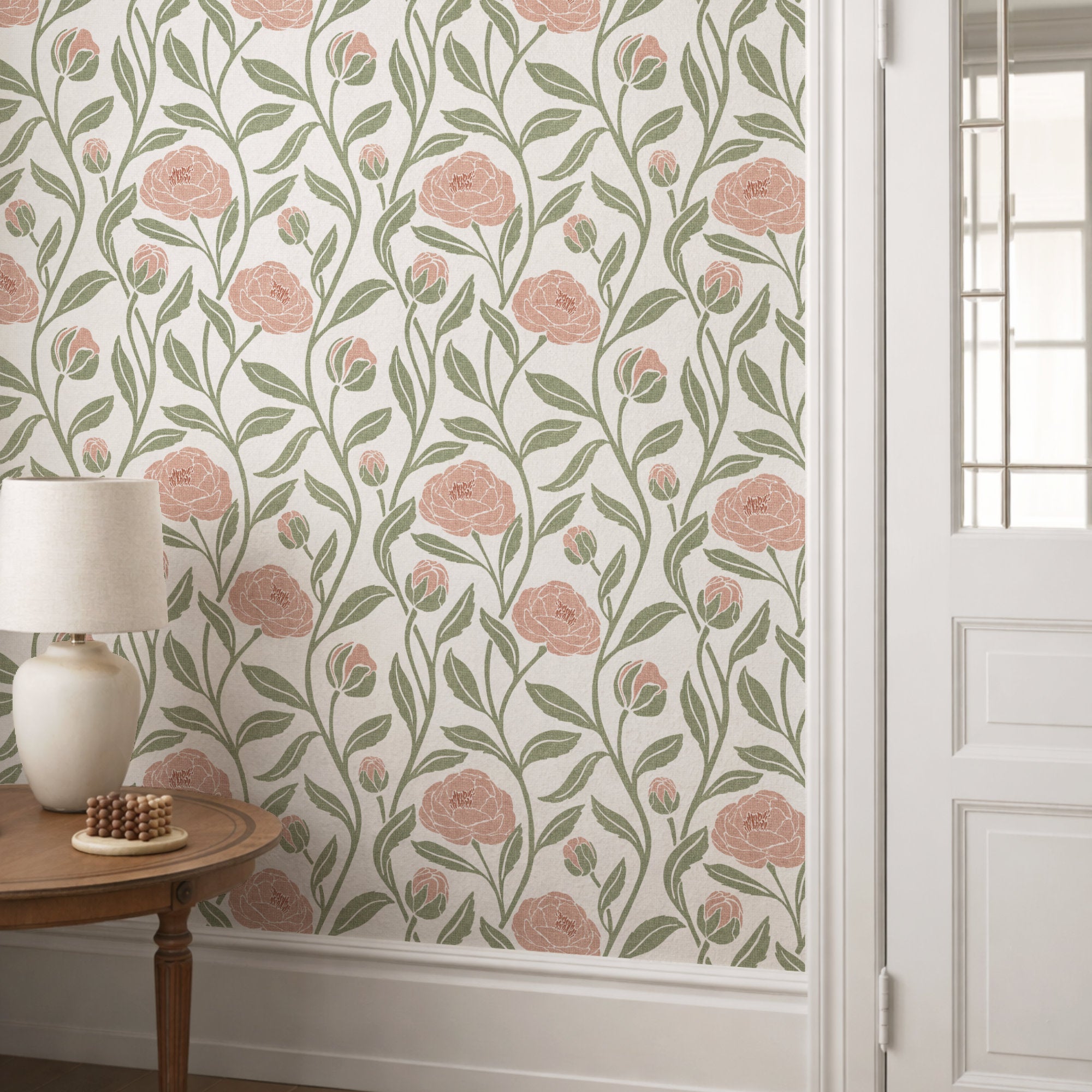 Blush pink peony flower wallpaper behind a lamp table, trailing peonies with sage leaves on cream