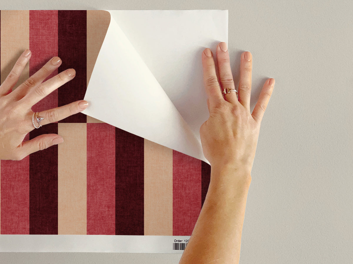 Burgundy and cream staggered block stripe wallpaper sheet being applied on wall