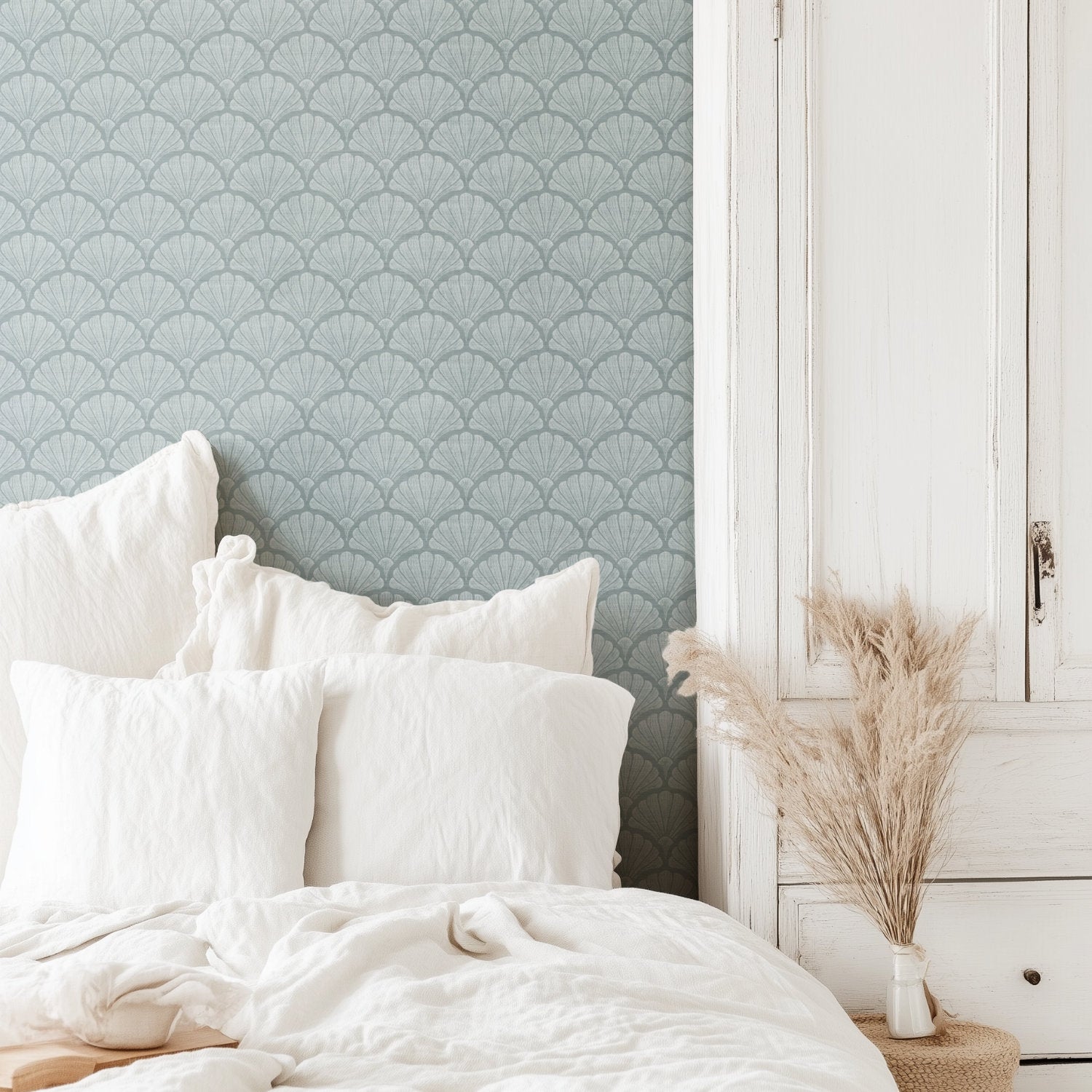 Light blue scallop shell wallpaper in a calm bedroom, hand-drawn fan shells behind a white bed with pillows and dried grasses