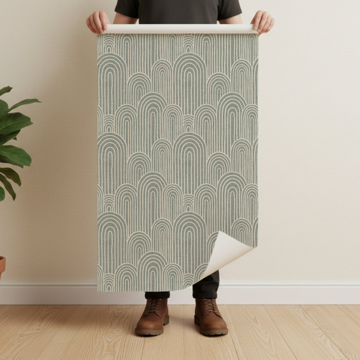 Scandinavian arches wallpaper in sage green held by man showing full pattern repeat