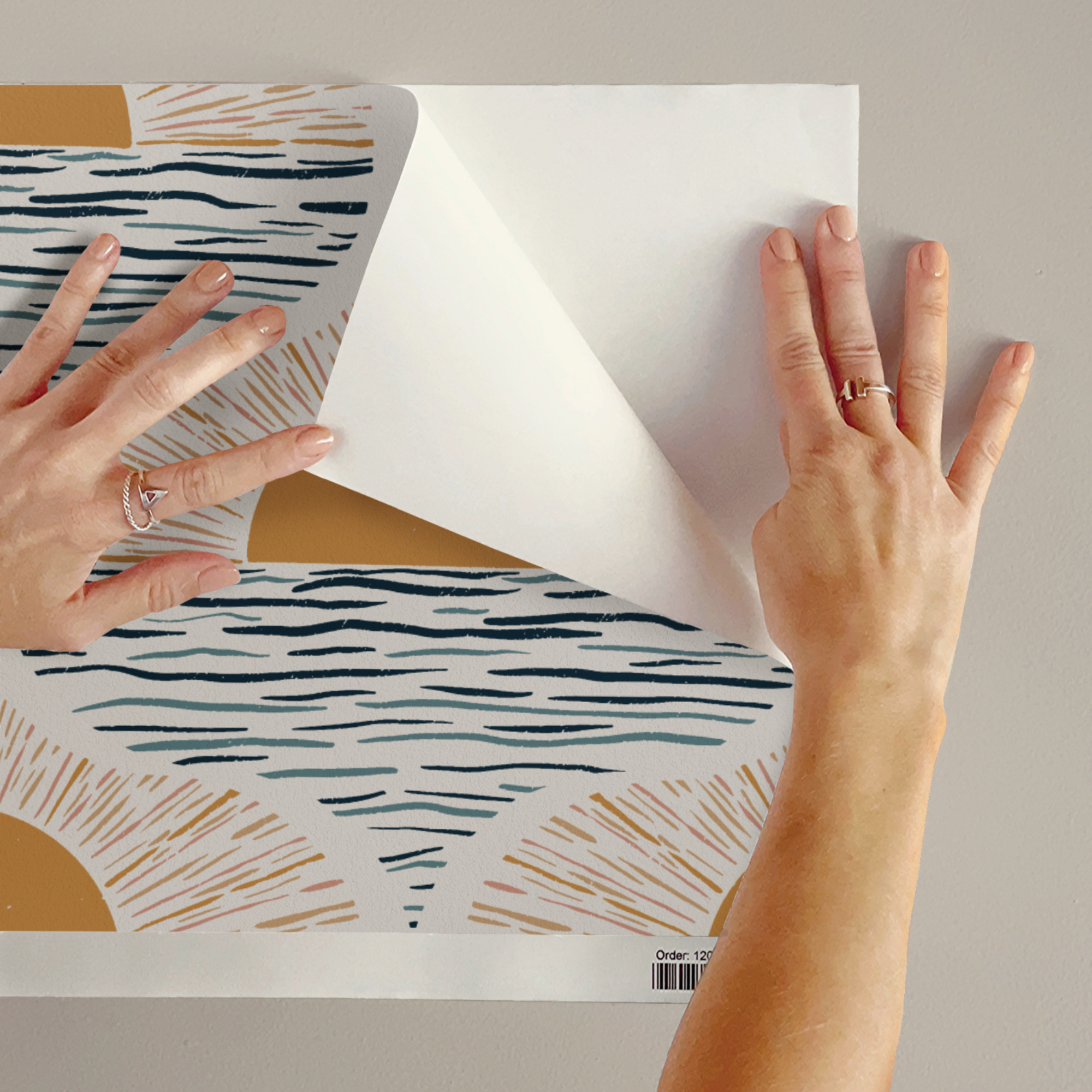 Applying peel-and-stick boho coastal wallpaper with sunrise over ocean design in yellow and blue