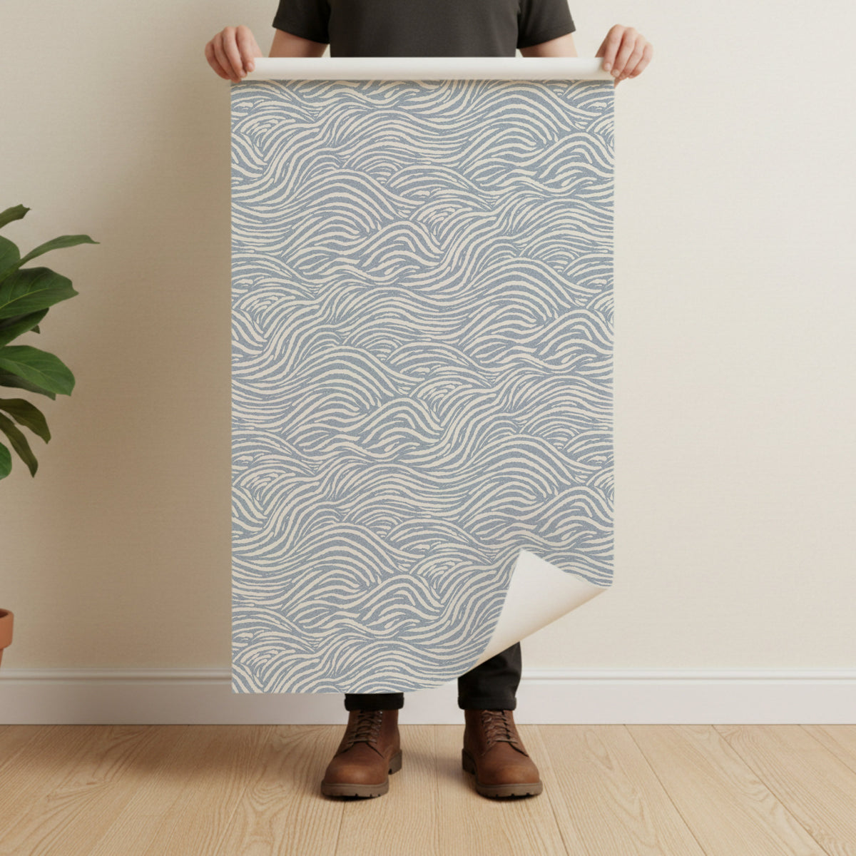 Person holding a large sheet of paper with coastal waves line pattern against a plain wall.