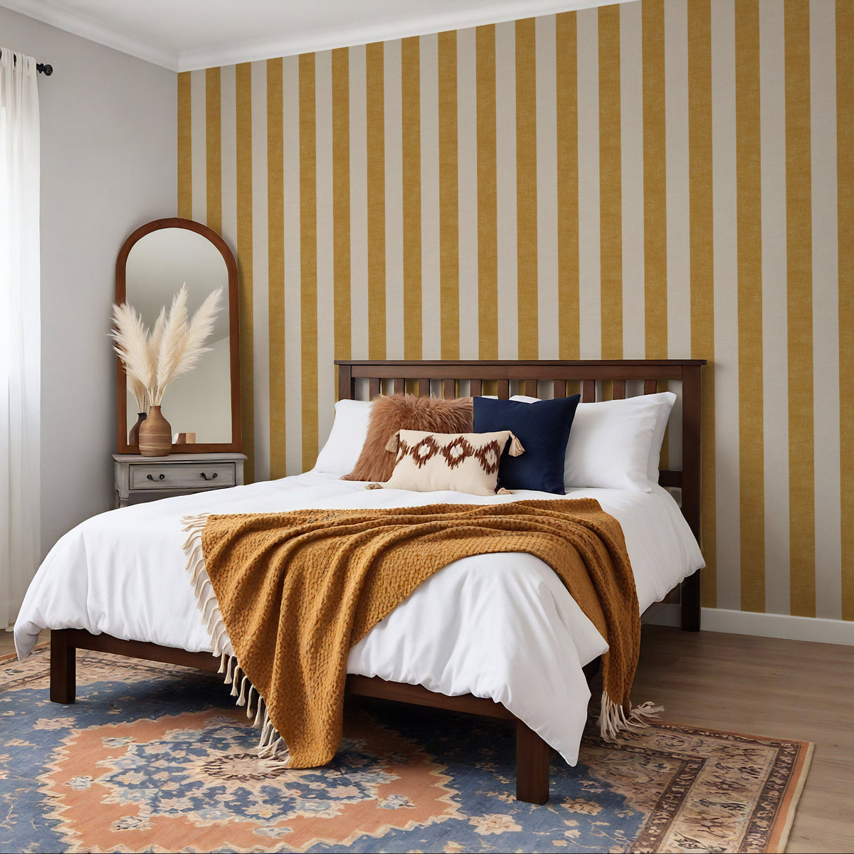 Wide stripe wallpaper in ochre yellow in a cosy bedroom setting with warm tones and wooden furniture