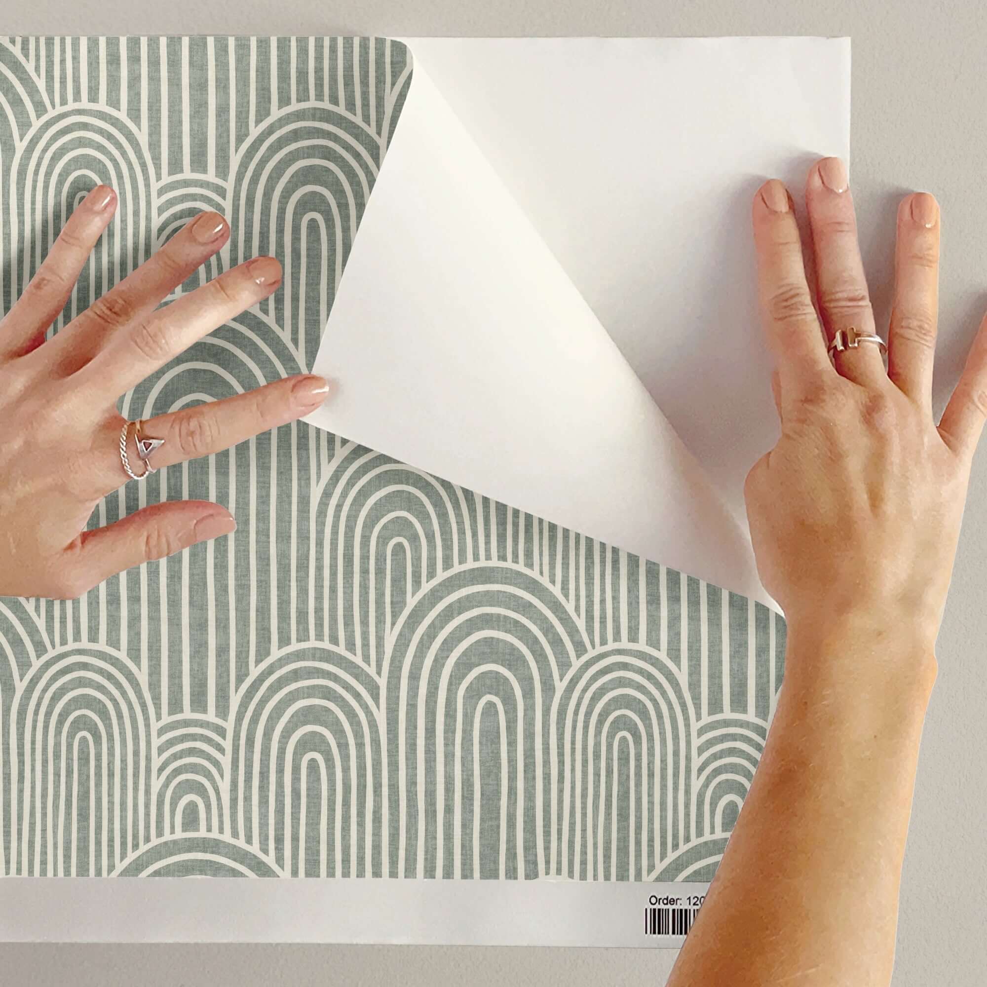 Hands holding a peel and stick wallpaper sample, exploring if is peel and stick wallpaper good for home decor.