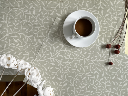 Flatlay of Japandi botanical grasscloth wallpaper in sage with white floral design, styled with a coffee cup and neutral decor accents.