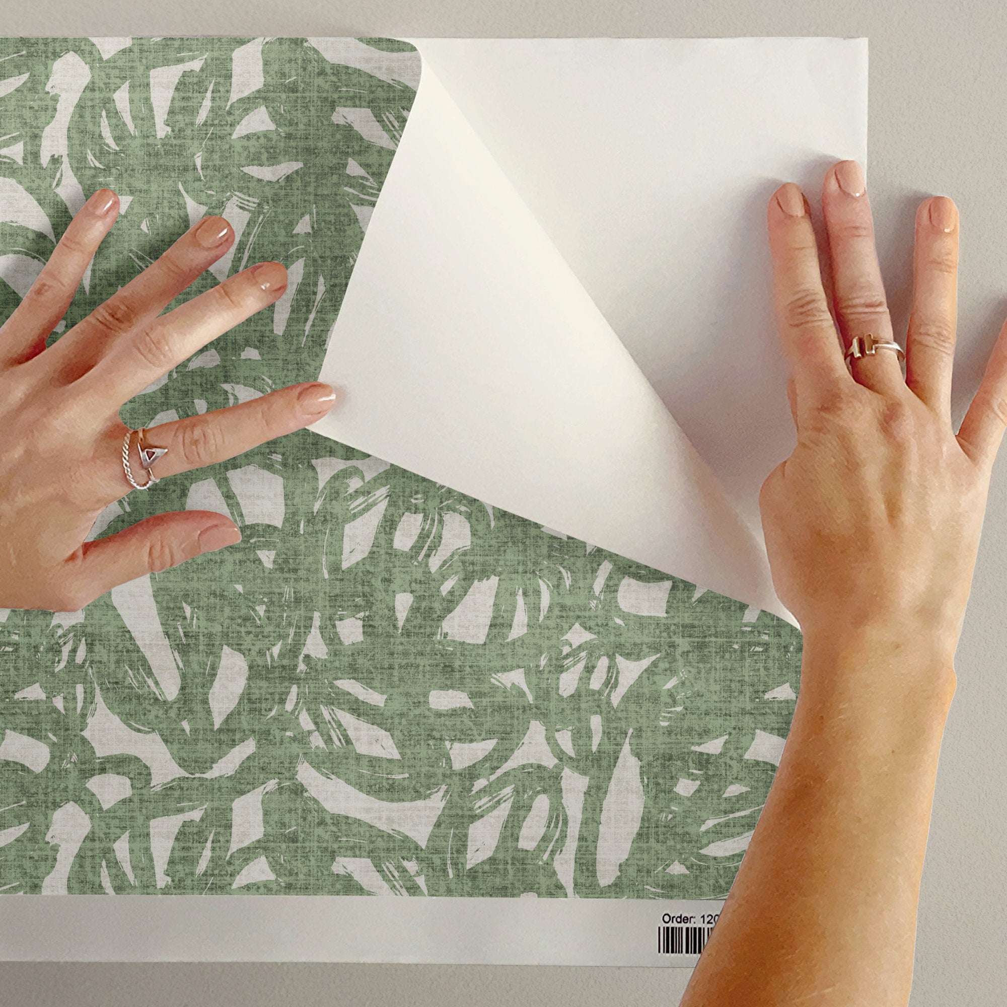 Green abstract brushstroke wallpaper sample being peeled or layered with hands