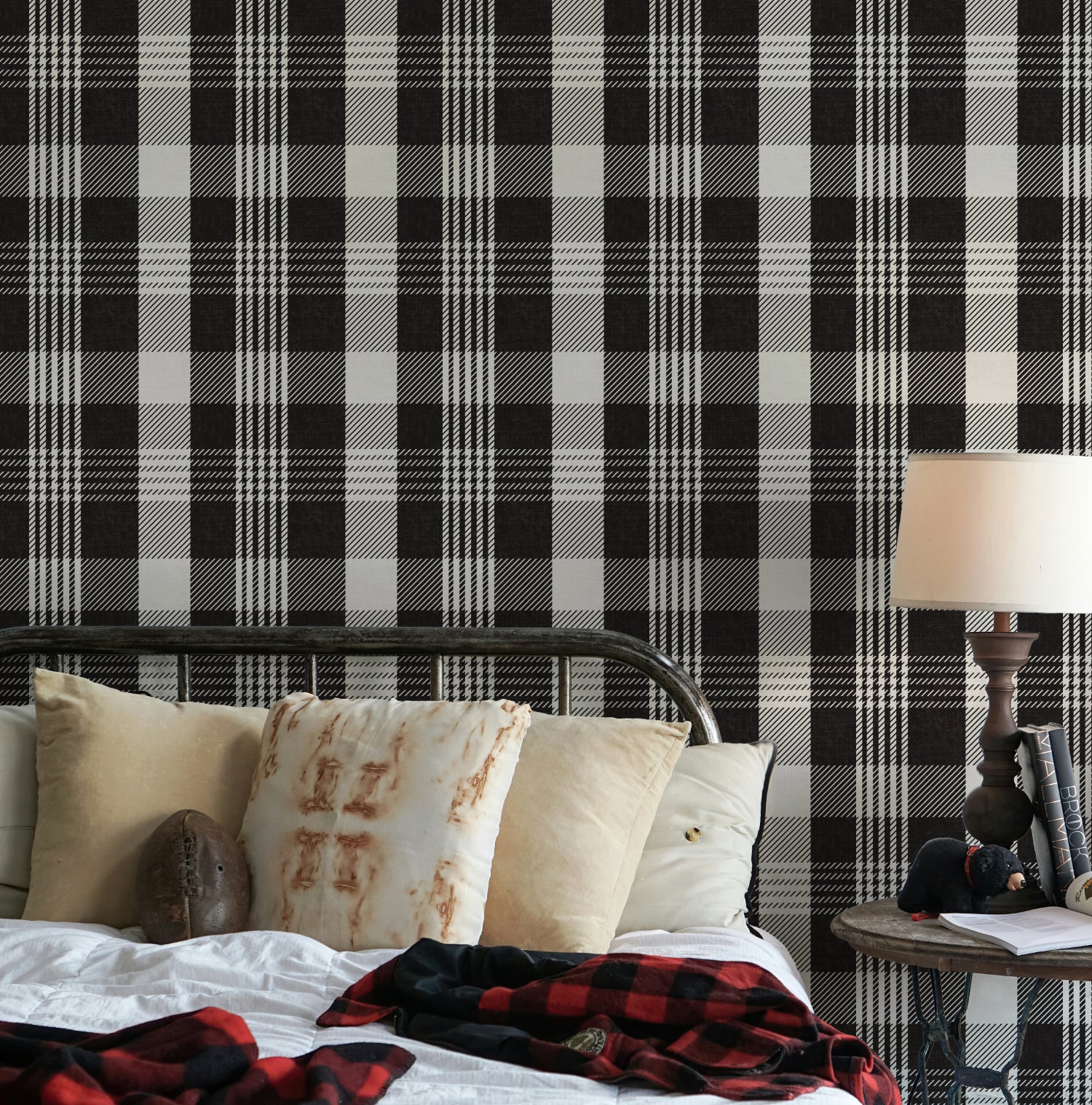 Black checkered wallpaper with a bold plaid design as a bedroom feature wall, styled with layered neutral pillows and cosy bedding