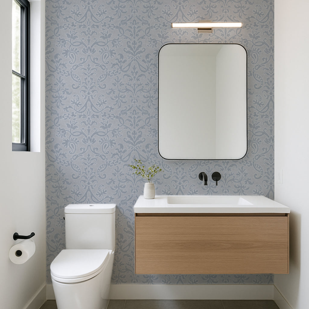 Blue Victorian damask floral wallpaper in a modern bathroom with wooden vanity and round mirror.