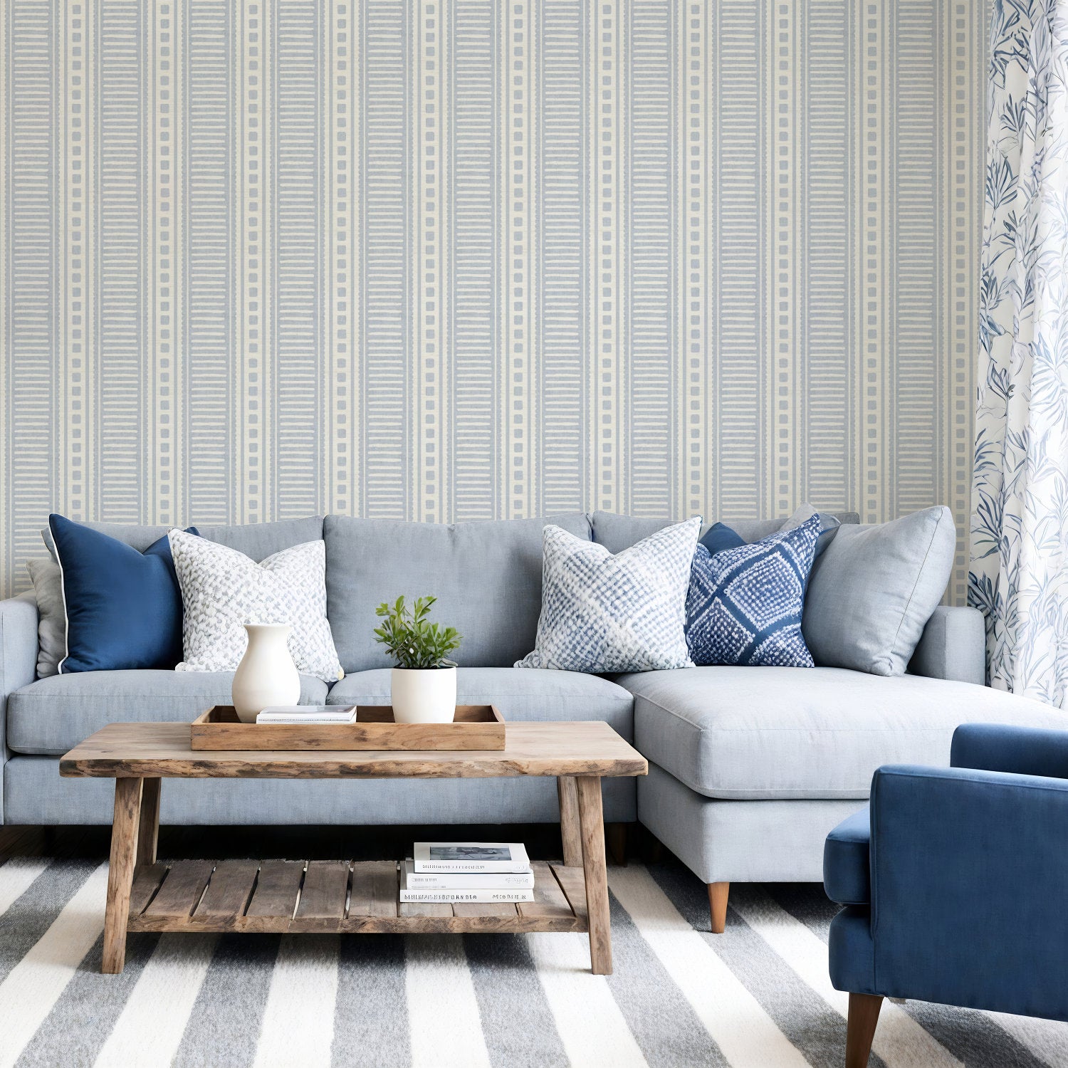 Cornflower blue coastal stripe wallpaper on a living room feature wall behind a grey sofa with blue cushions and a striped rug