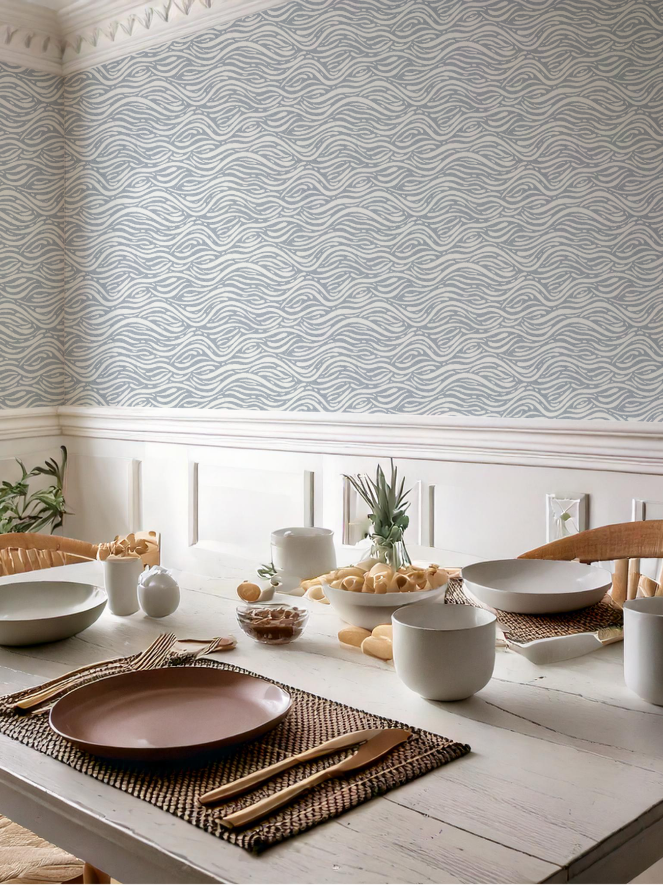 Dining room styled with coastal waves wallpaper. The room has a table set for a meal against a patterned wall.
