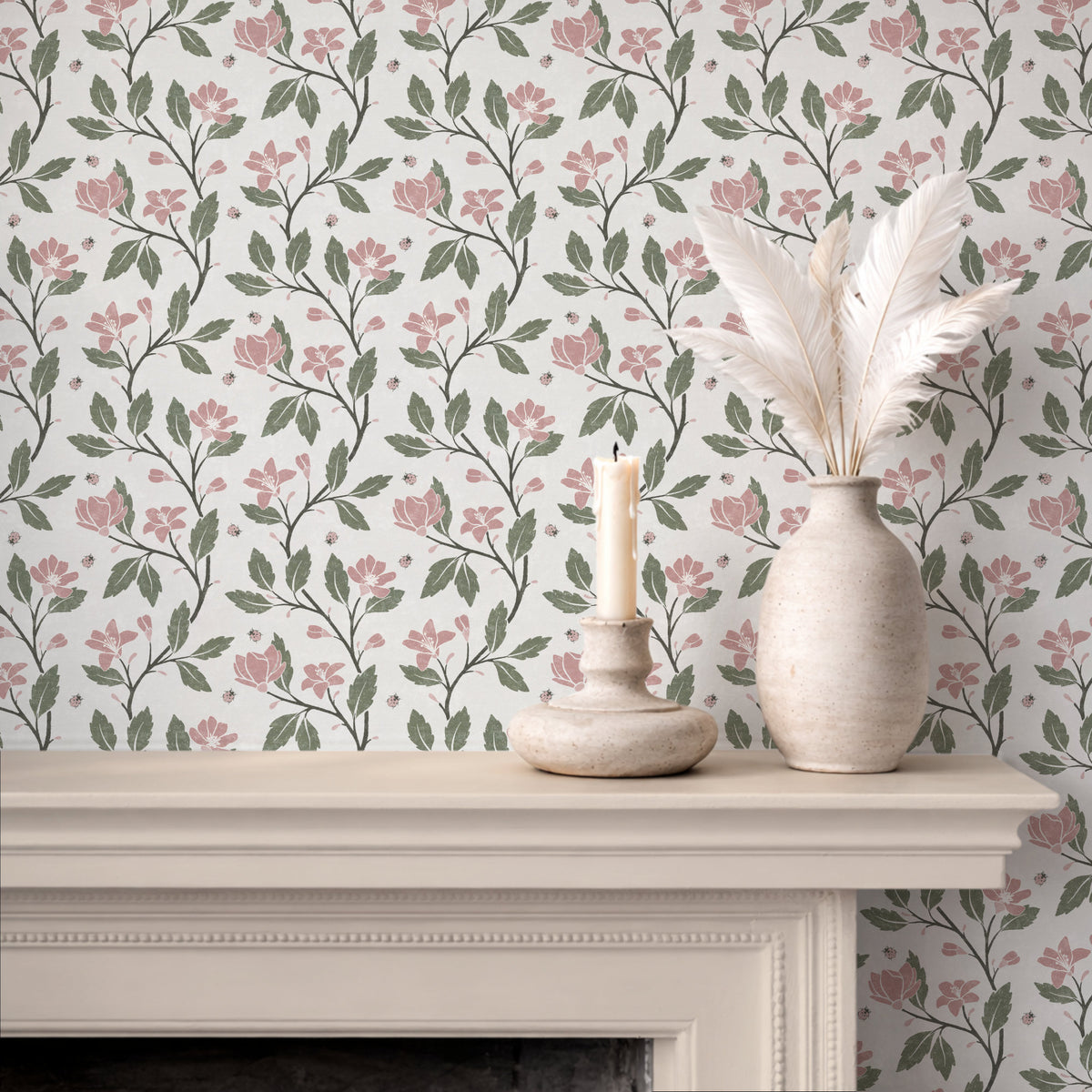 Pink and green cottage floral wallpaper on chimney breast with candle and pampas grass decor