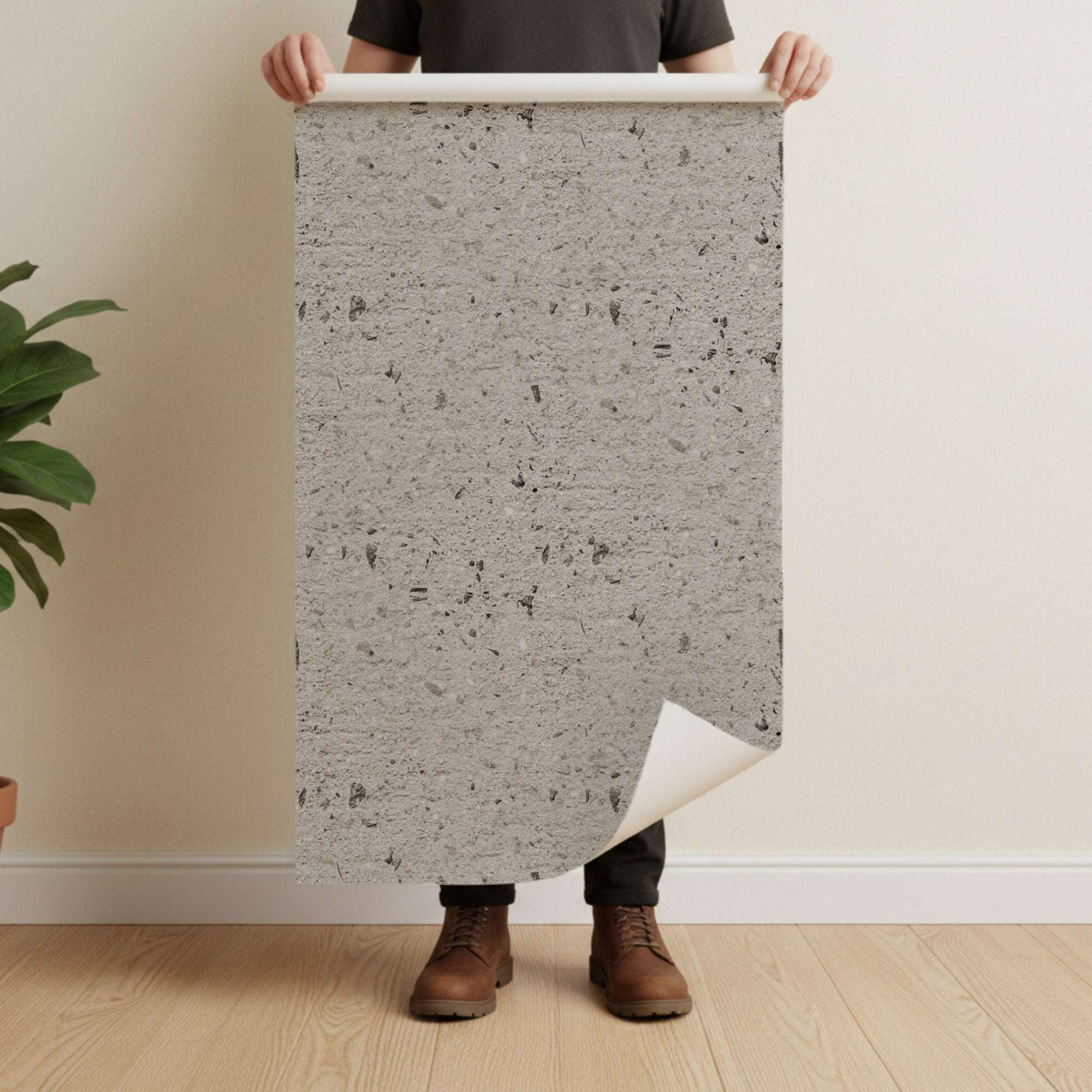 Concrete-effect wallpaper sheet held up for installation, light grey speckled texture