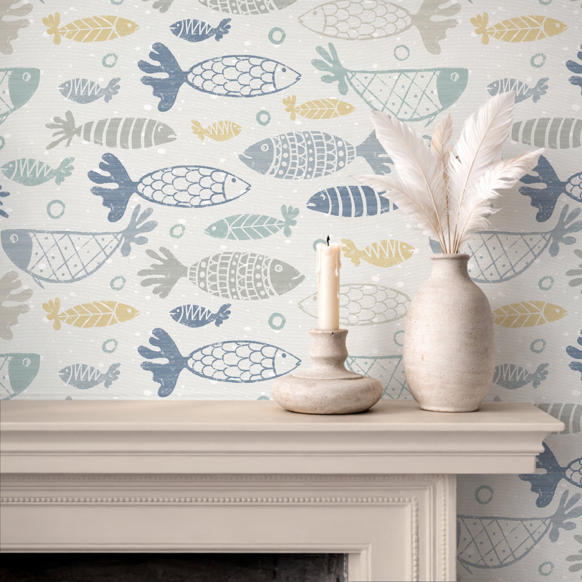 A styled interior scene showing a fireplace mantel with patterned muted multicoloured school of fish wallpaper, a white feather vase, and a candle holder with a lit candle.