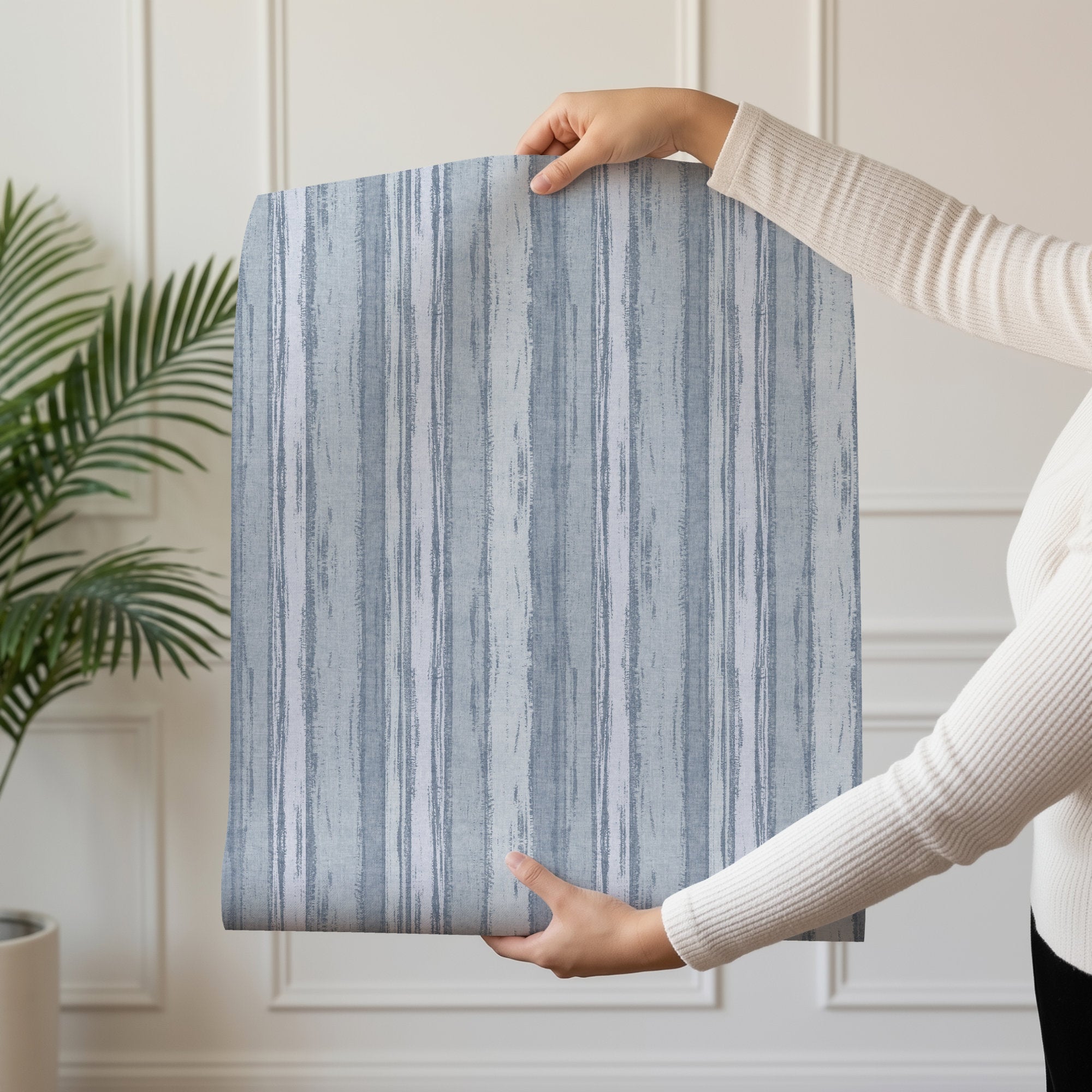 Hand holding Abstract Stripe Wallpaper with textured blue and gray tonal stripes showcasing organic movement.