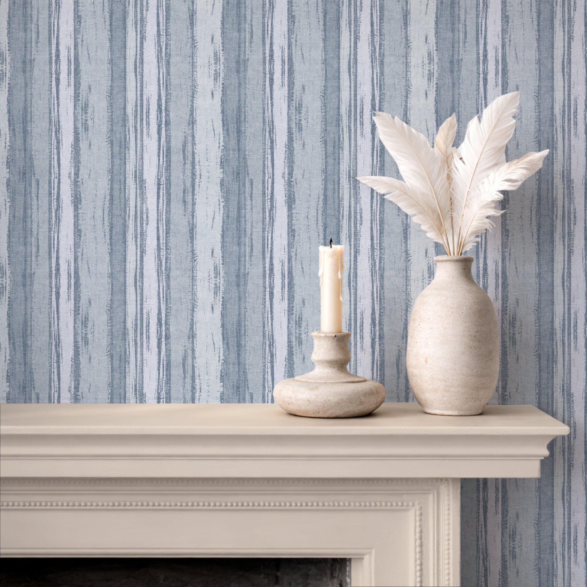 Abstract stripe wallpaper in soft blue tones with a candle and vase on a mantel.
