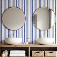Painted stripe wallpaper in blue and white in bathroom with round mirrors and twin basins