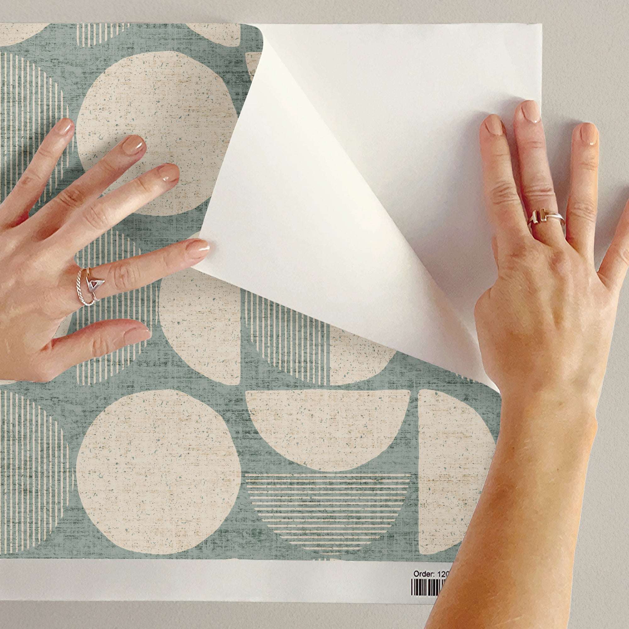 Mid-century circle-pattern wallpaper backing held by hands, teal and beige