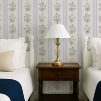 Blue and yellow floral stripe wallpaper in twin bedroom with white beds and brass lamp