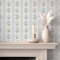 Blue floral stripe wallpaper above fireplace with candle and ceramic vase