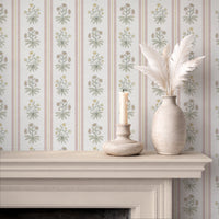 Pink floral stripe wallpaper above fireplace with candle and ceramic vase