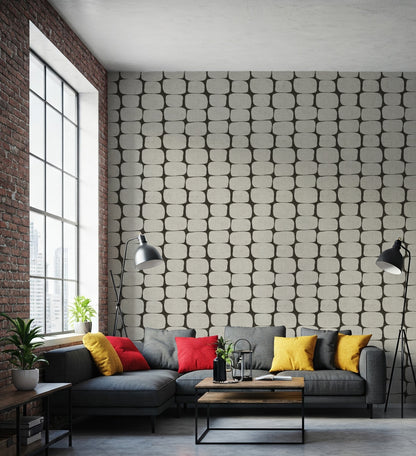 Modern clack and white geometric wallpaper in a  living room with a gray sectional sofa, colorful pillows, and a textured wall.