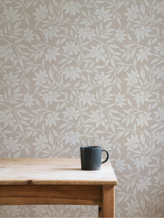 Light-filled dining room with a wooden table against taupe Japandi botanical wallpaper featuring stylised lotus leaves