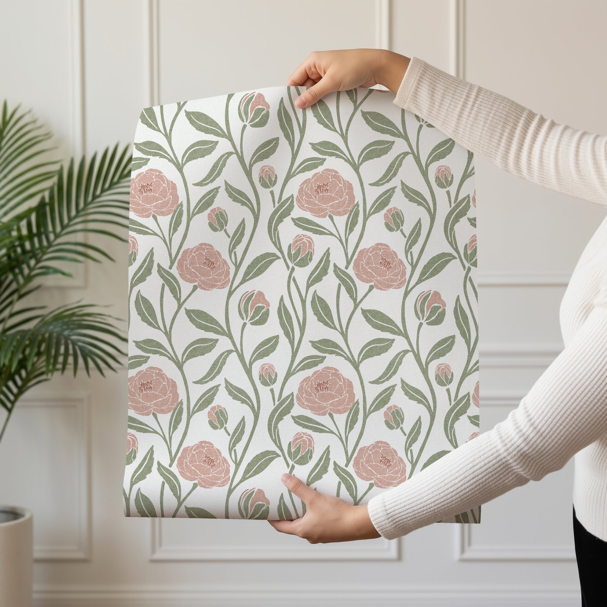 Person holding a roll of blush pink peony flower wallpaper with trailing peonies