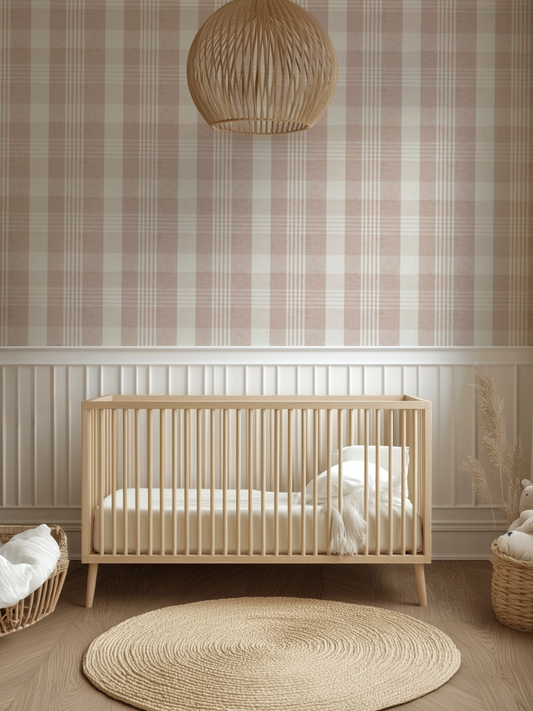 Pink plaid wallpaper with a soft modern check design in a nursery, featuring a natural wood cot and round jute rug for a cosy baby’s room