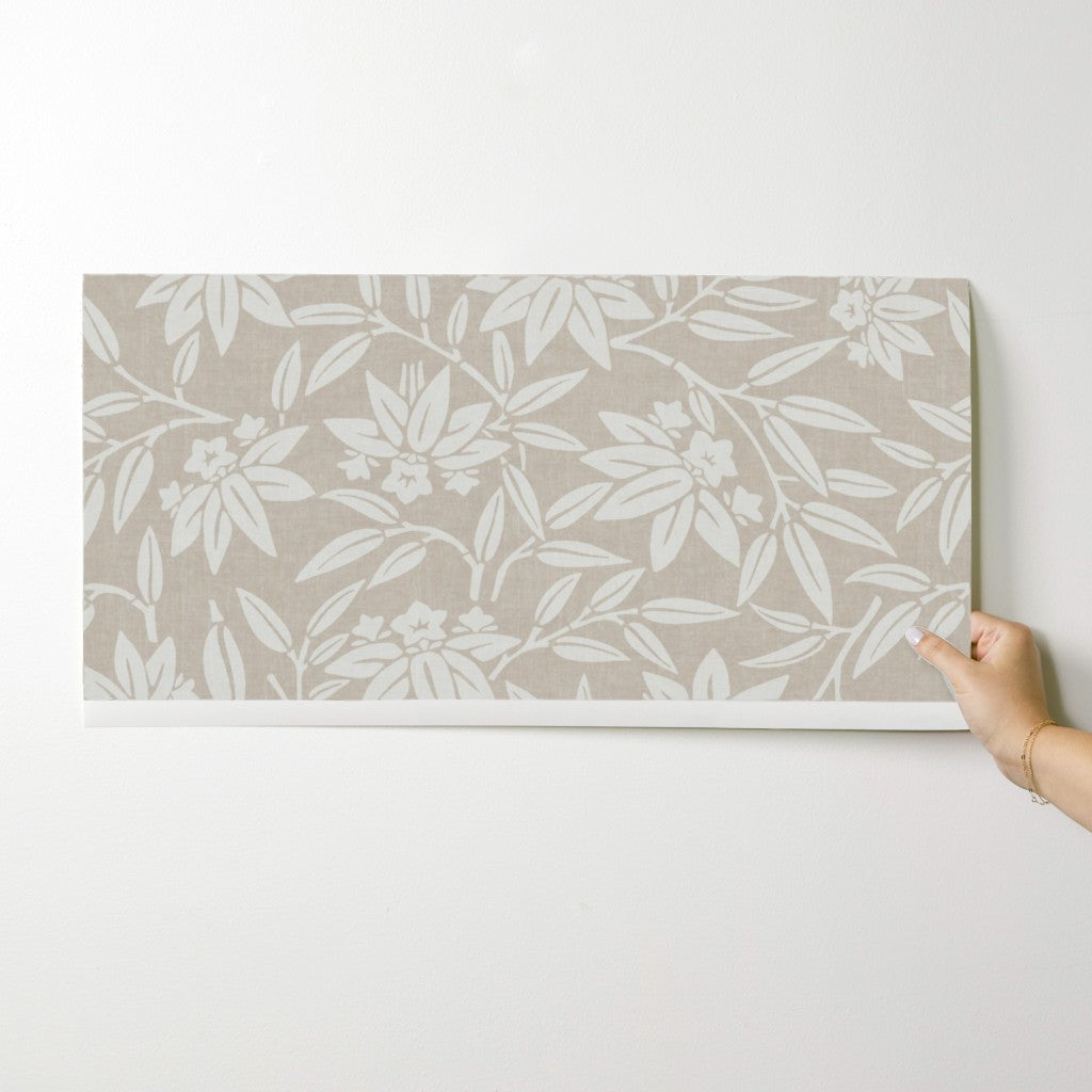 Rolled taupe wallpaper showing the Japandi botanical pattern of flowing lotus leaves and blooms