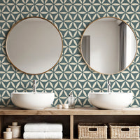 Teal blue geometric wallpaper in bathroom with double basins and round gold mirrors
