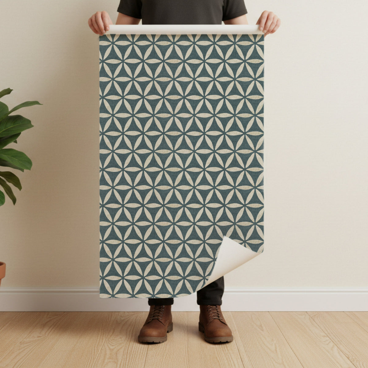 Geometric wallpaper in teal blue held by man showing full pattern repeat