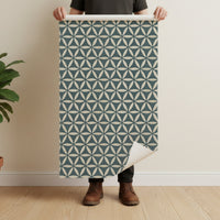 Geometric wallpaper in teal blue held by man showing full pattern repeat