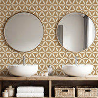 Ochre yellow geometric wallpaper in bathroom with double basins and round gold mirrors