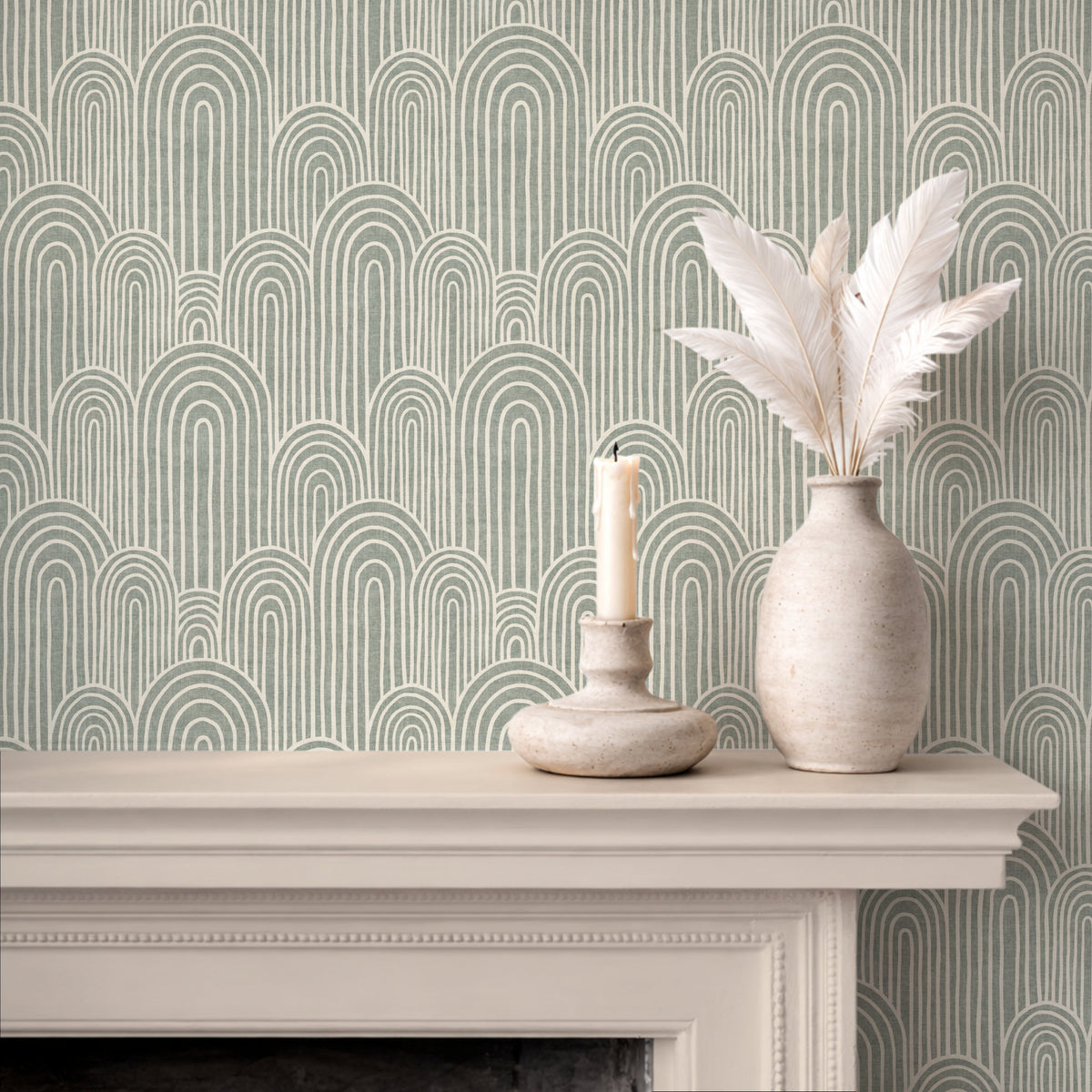 Arches wallpaper in light sage green above fireplace with candle and ceramic vase