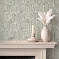 Arches wallpaper in light sage green above fireplace with candle and ceramic vase