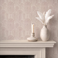 Dusty pink arches wallpaper above fireplace with white candle and ceramic vase