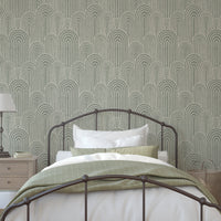 Sage green Scandinavian arches wallpaper behind a metal bed in a modern bedroom with white bedding