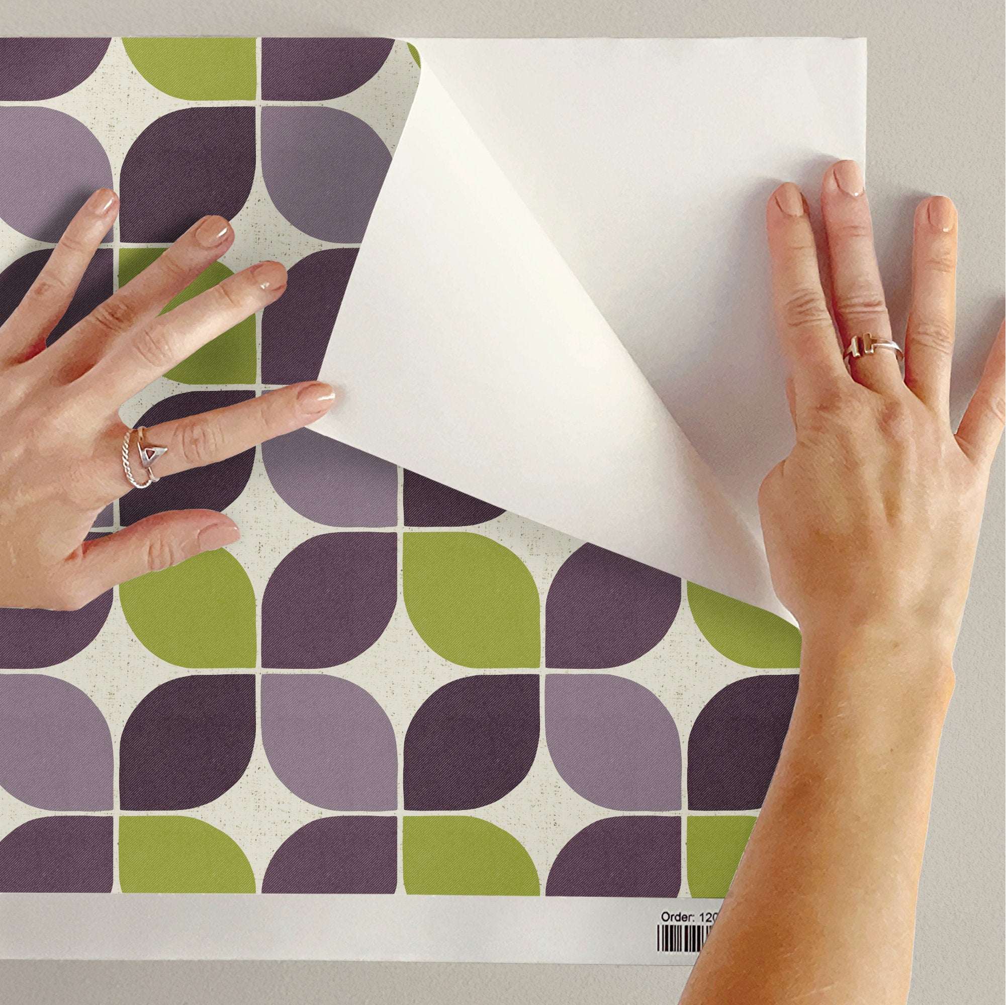 Geometric square wallpaper being applied; plum and green shapes on a light base