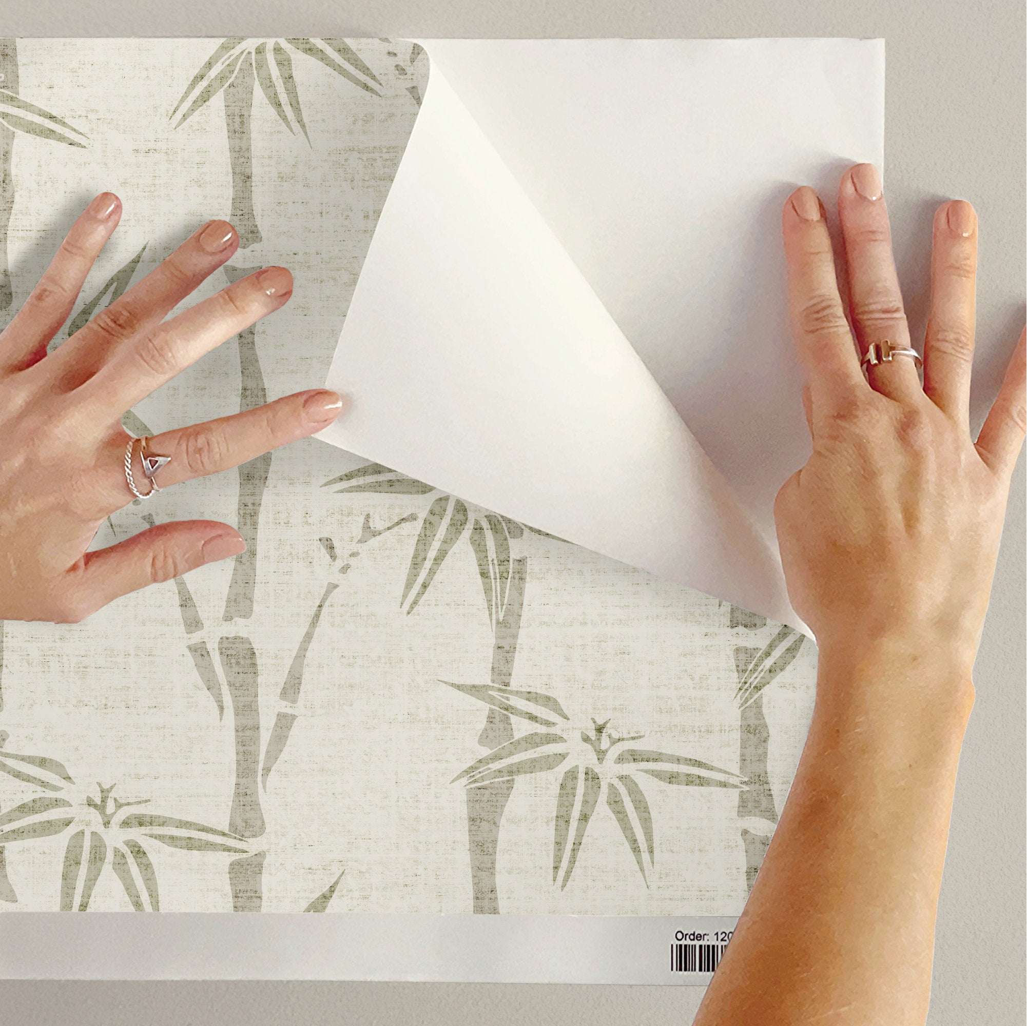 Bamboo wallpaper being applied: off-white panel with light green stalk and leaf pattern