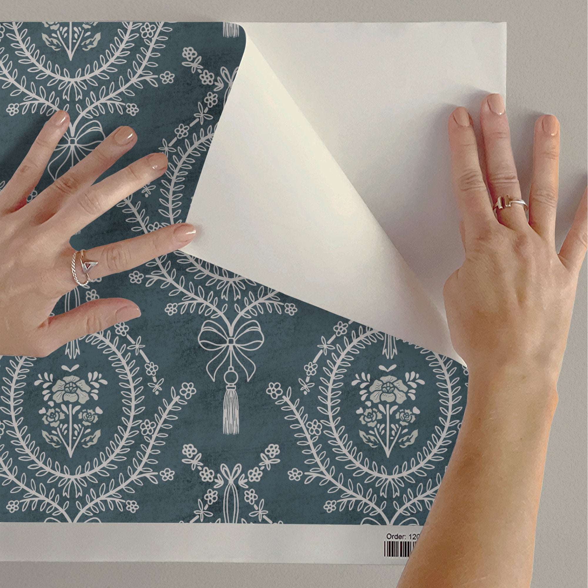 Mauve floral wallpaper sheet with repeating medallions, bows, and hanging tassels.