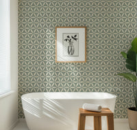 Teal geometric wallpaper with flower of life pattern in a modern bathroom with a white bathtub and framed art