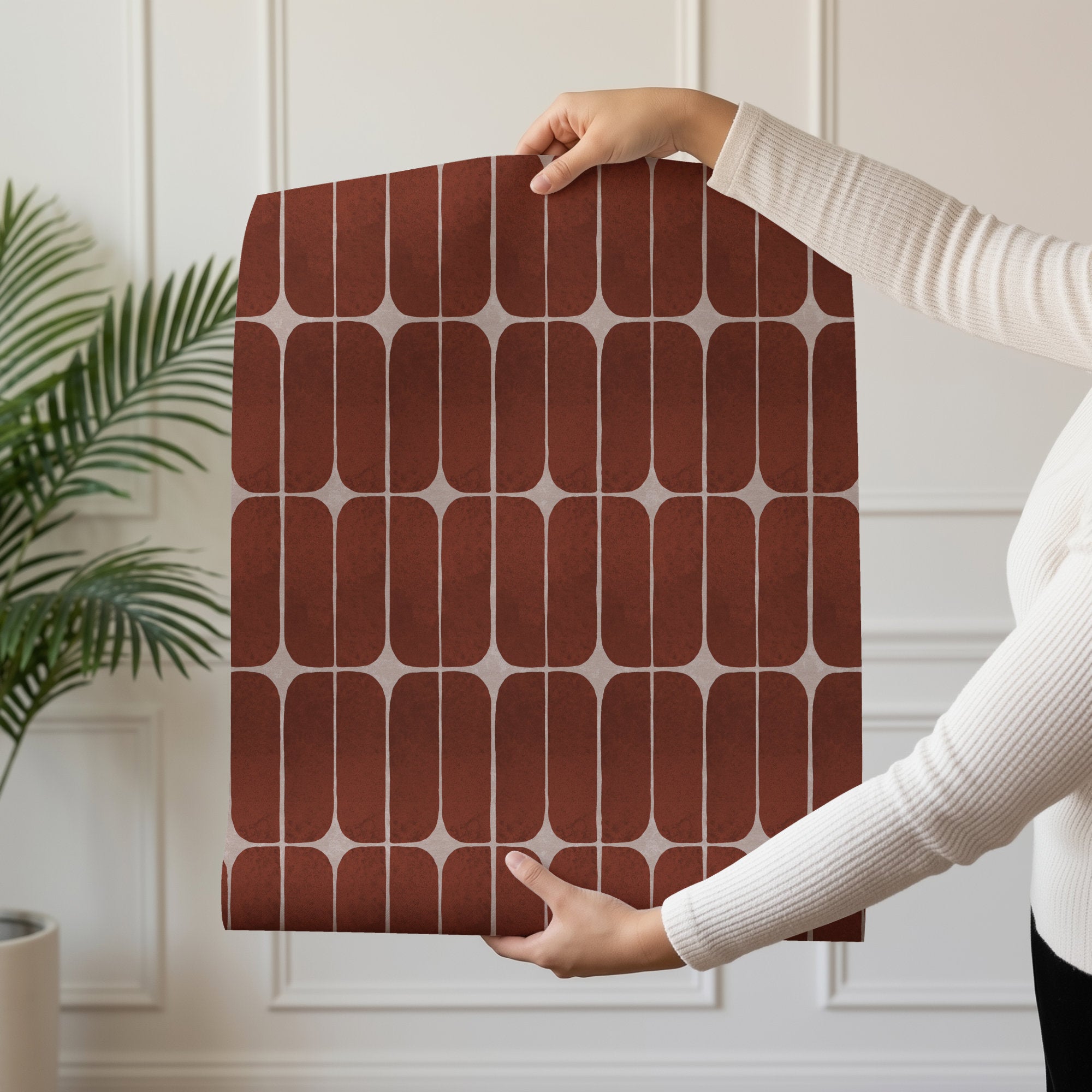 Person holding a roll of terracotta retro tile wallpaper with mid-century stadium pill tiles