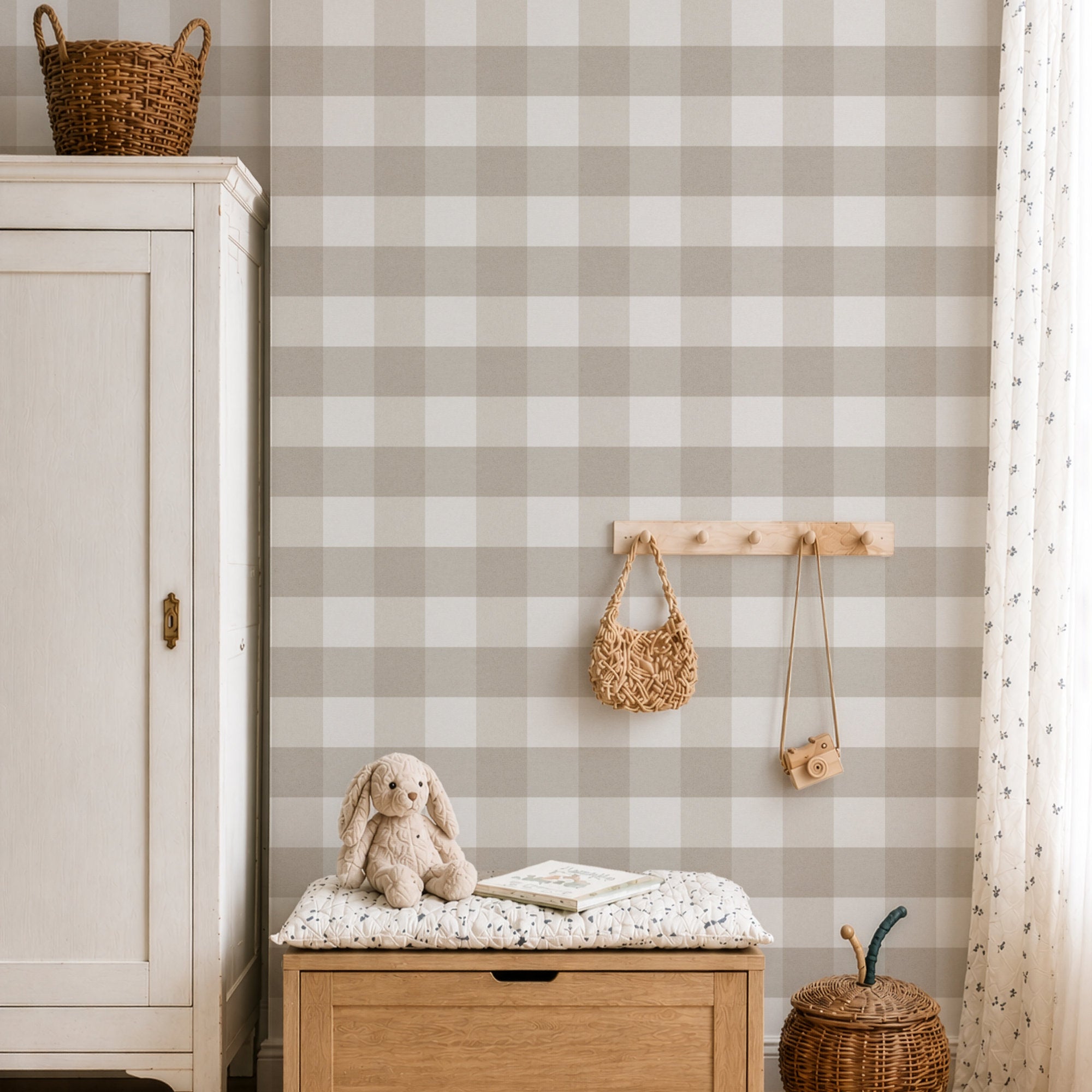 A styled interior corner with a wall covered in light beige and white checked gingham wallpaper. A wooden toy organizer rack hangs on the wall holding a woven bag and a small camera.
